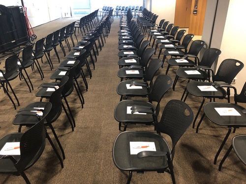 Neatly arranged meeting room chairs with distributed writing materials